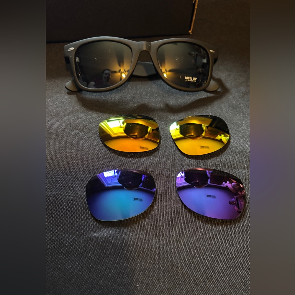 Sunglasses with three interchangeable lenses, dark, yellow, and blue.